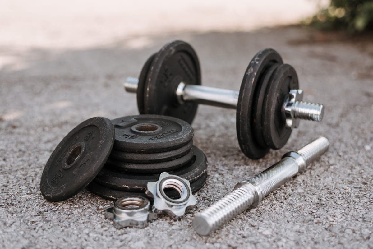 A pair of adjustable dumbbells on the floor of a home gym