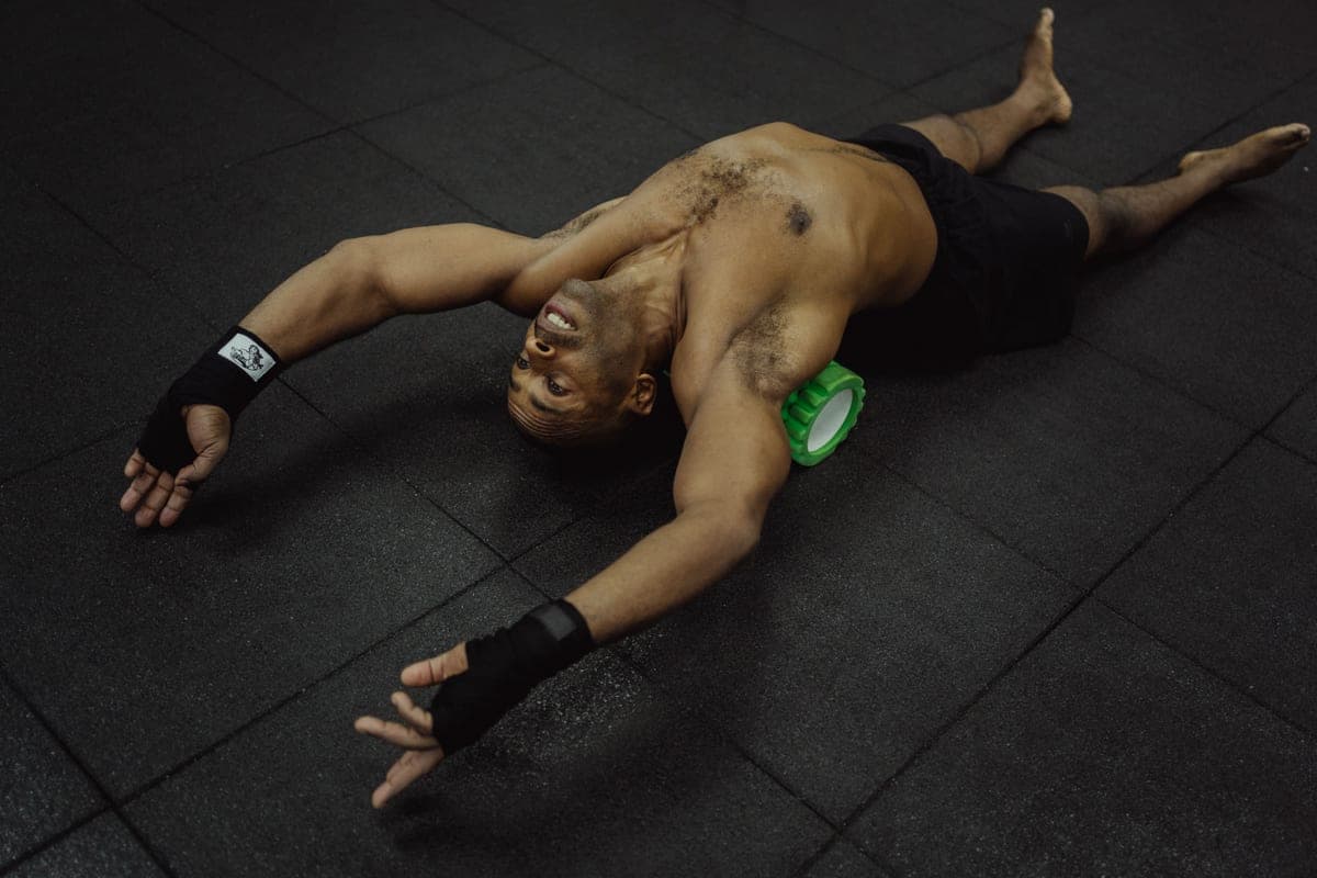 A massage gun and foam roller on a yoga mat