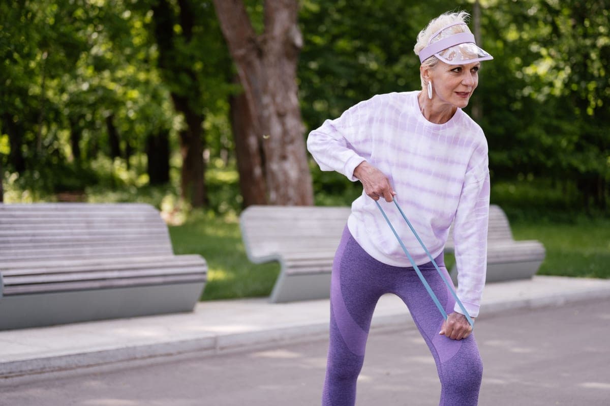 An older adult exercising at home with resistance bands